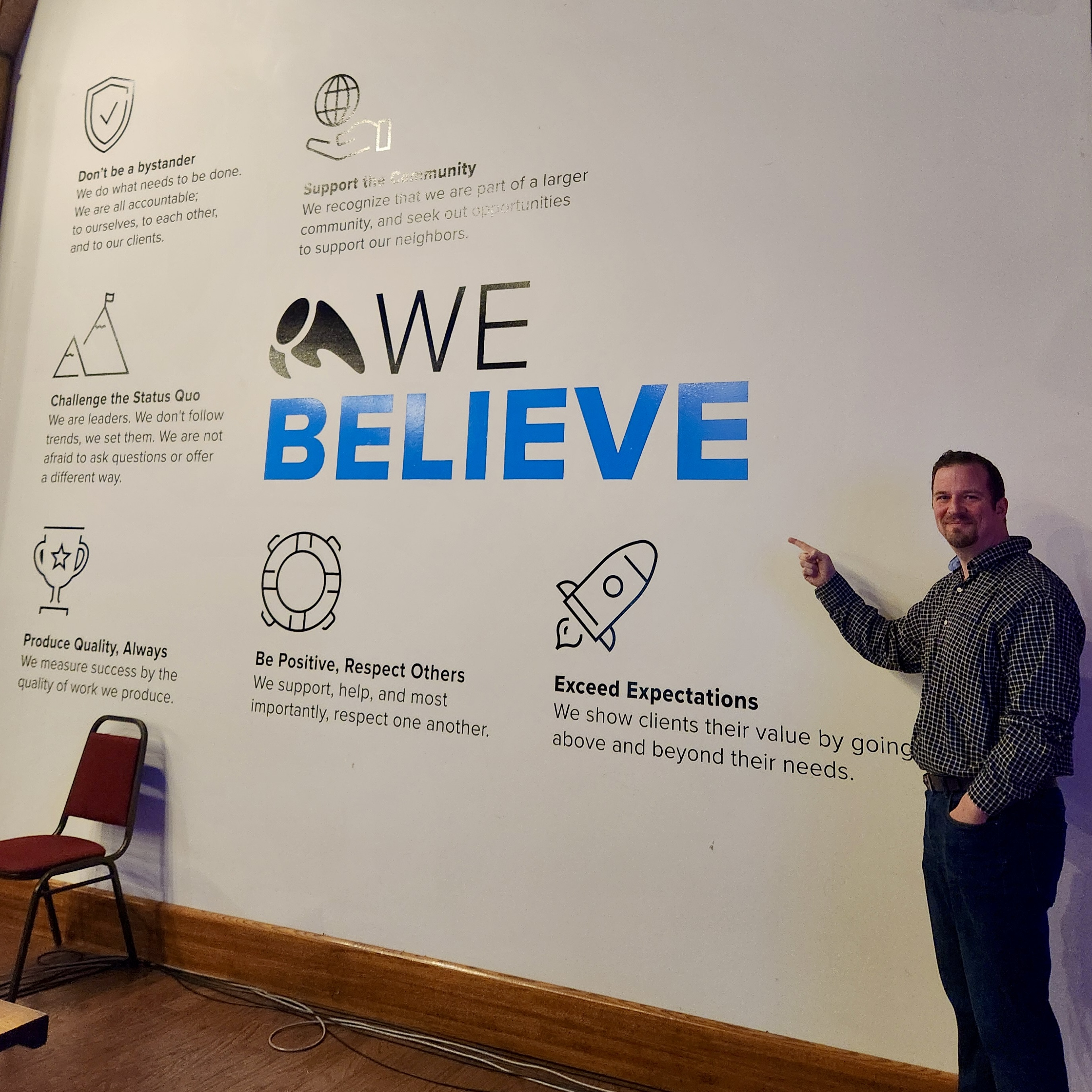 Dan O standing in front of Overit's Core Values wall 