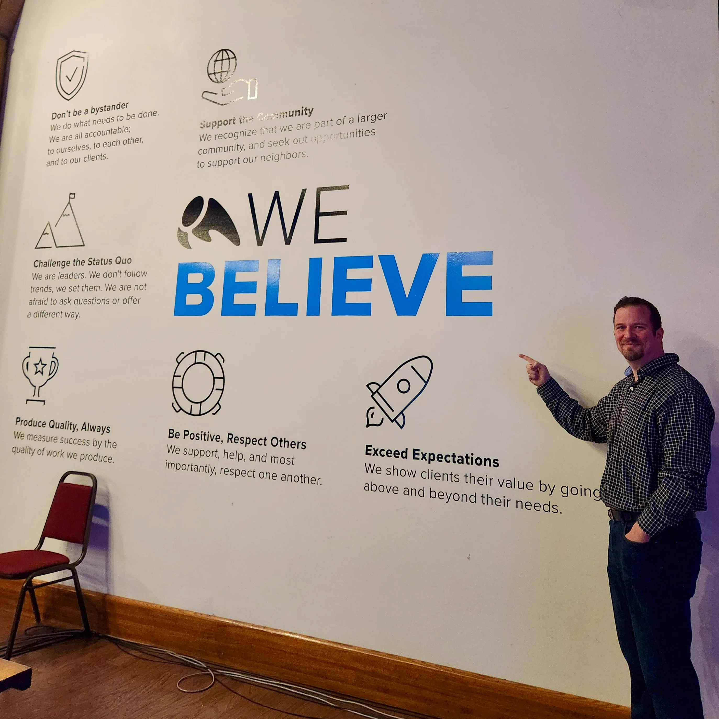 Dan O standing in front of Overit's Core Values wall